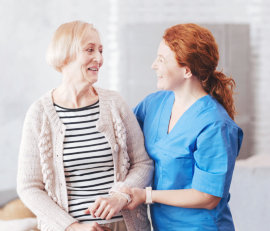 caregiver and elderly woman smiling at each other