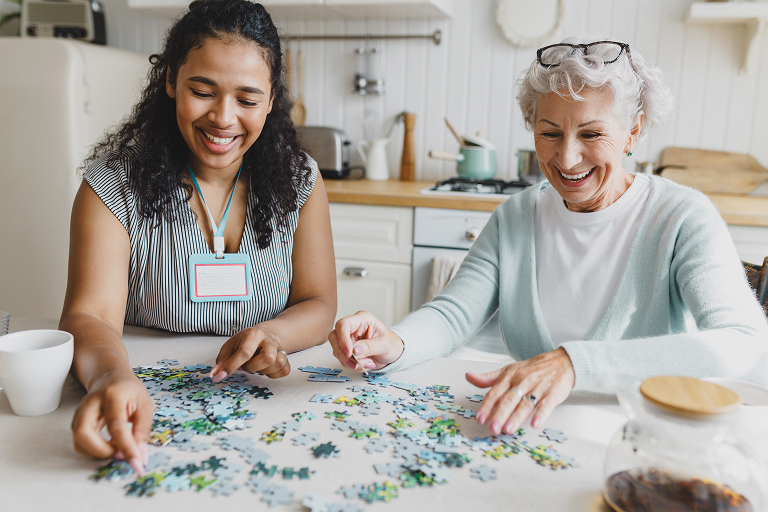 Caregiver providing companion care and puzzling with elderly woman